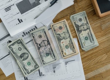 foto de planillas y dinero en efectivo en un escritorio