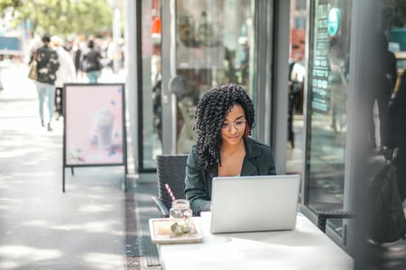 Persona sentada en la parte exterior de un restaurante trabajando en una laptop